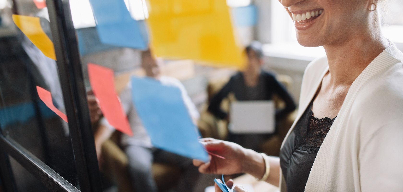 woman smiling and putting sticky notes on the wall