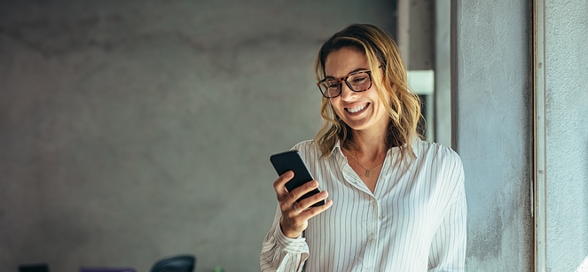 woman smiling while looking at her phone