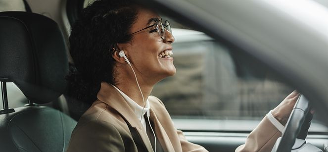 woman smiling and driving in her car