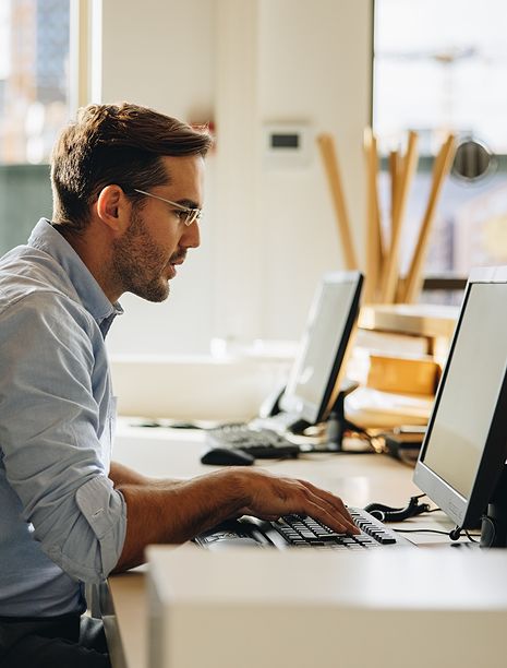 Man working at desk using computer for association management software and membership database management